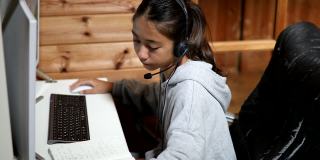 一个年轻的女孩在家里通过电脑在线课程学习