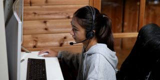 一个年轻的女孩在家里通过电脑在线课程学习
