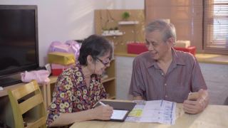 亚洲老男人和女人使用手机扫描和支付家庭财务账单视频素材模板下载