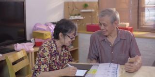 亚洲老男人和女人使用手机扫描和支付家庭财务账单