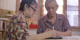 亚洲老男人和女人使用手机扫描和支付家庭财务账单