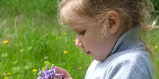 快乐的孩子在户外享受大自然。春天。美丽的白日梦小女孩捧着一束春天的鲜花