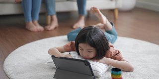 小女孩和父母坐在沙发上，在数码平板电脑上画画