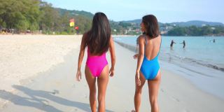 亚洲女性朋友一起在夏日阳光灿烂的沙滩上散步