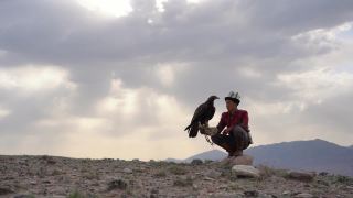 鹰猎人坐在吉尔吉斯斯坦山脉的背景视频素材模板下载