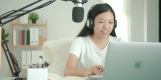 亚洲女学生或女商人远程工作和播客从家里与电脑笔记本电脑。社交距离概念在covid-19疫情下独自在家工作。