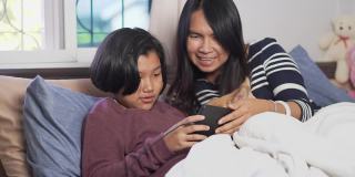母女二人用平板电脑视频通话，在卧室里和狗狗玩耍。幸福的家庭的概念。