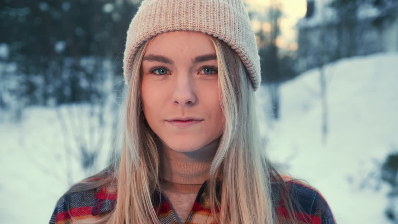 幸福年轻美丽冷静的20多岁女人的肖像看着相机摆姿势，微笑在雪山冬季森林慢镜头。
