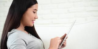 亚洲女性用数码平板电脑上网购物、打电话、发短信，用互联网科技生活着笑脸。亚洲女性触控智能平板电脑专注于手用移动应用家庭办公。