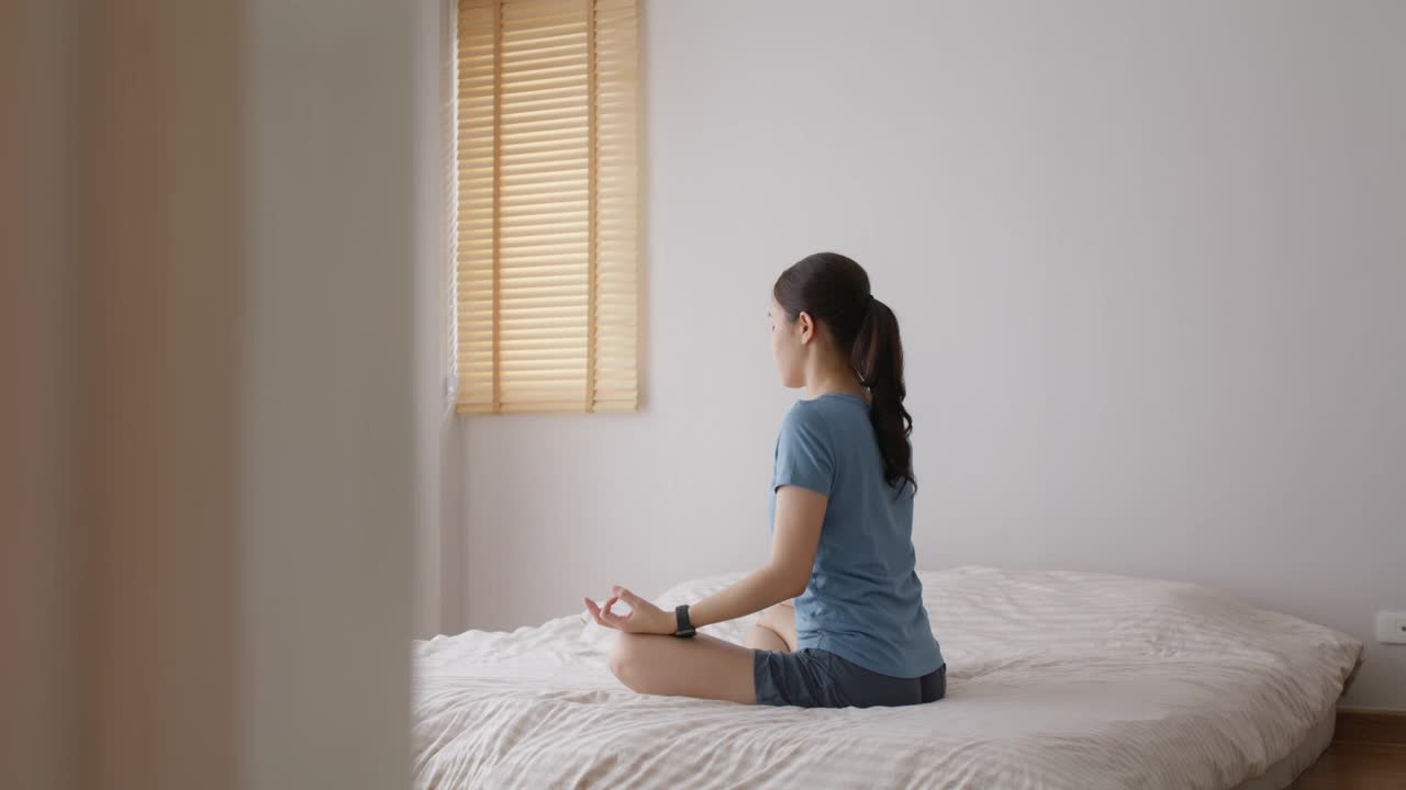 亚洲人早起健康生活平衡的好处瑜伽姿势在床上。