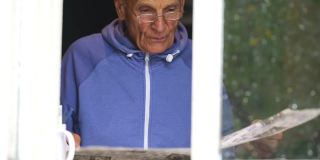 一名退休男子在窗外玩填字游戏