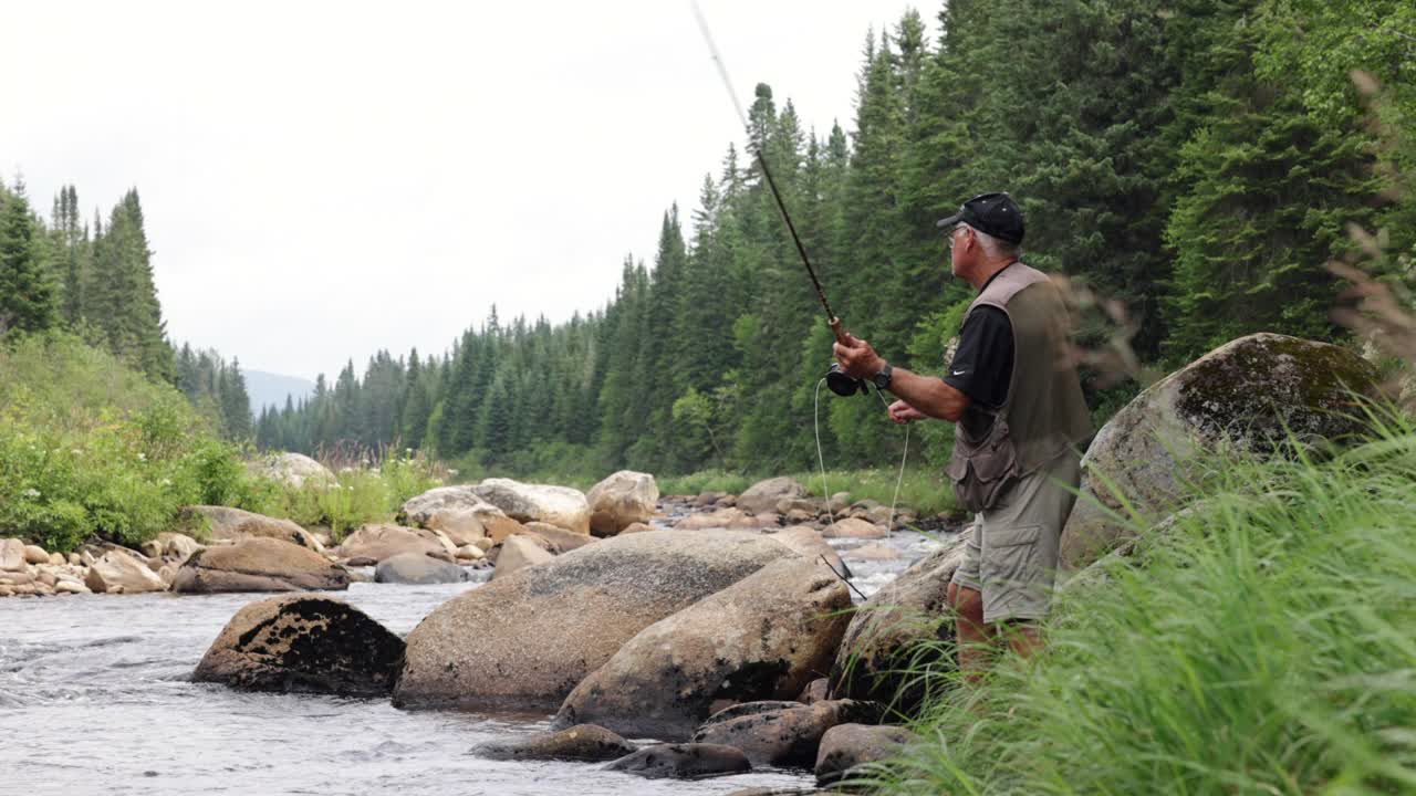 一位老人在魁北克的河里用假蝇钓鱼