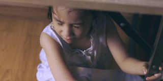 俯视图的亚洲小女孩在桌子下哭泣，悲伤，压抑，痛苦，不安和害怕的表情，这是由于家庭惩罚和暴力，这是社会问题。