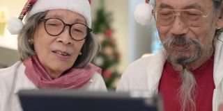 亚洲老年夫妇在圣诞节期间使用数字平板电脑或智能手机进行视频通话