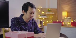 年轻的亚洲人使用电脑会议电话给惊喜和赠送圣诞礼物盒
