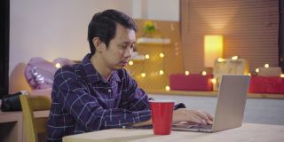 年轻的亚洲人使用电脑会议电话给惊喜和赠送圣诞礼物盒