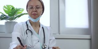 一名戴眼镜的白人女医生在诊所的办公桌前检查x光照片。放射科医师分析部分头部CT扫描并记录结果
