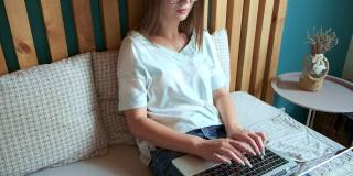 年轻女子用笔记本电脑快速敲击键盘工作，躺在卧室的床上，灵活的时间和远程工作。