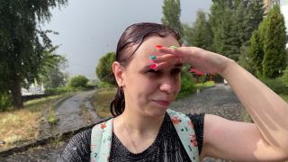 年轻的女人被雨淋湿了。在夏天的街道上，湿透的女性在倾盆大雨下用手遮住眼睛视频素材模板下载
