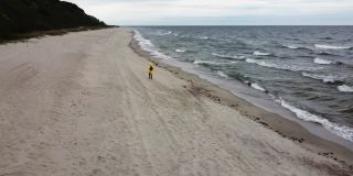 一名女子在狂风暴雨的海滩上奔跑，被无人机拍摄下来