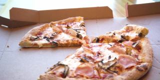 男子手拿着一片热披萨，披萨上有拉伸的奶酪，蓬松的披萨上有火腿、蘑菇和奶酪，男子手拿着一片披萨