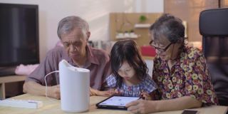 孙女帮助爷爷奶奶安装家用加湿器，同时使用数码平板电脑控制智能家居