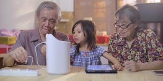 爷爷奶奶和孙女坐在客厅里用数码平板电脑控制智能家居设备使用电器