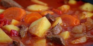 在红锅里炖土豆和红萝卜，煮开后咯咯地笑。