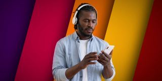 年轻的黑人男子使用智能手机应用，戴着耳机欣赏最喜欢的音乐