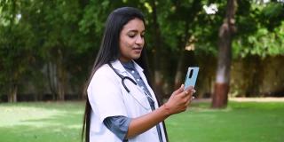 年轻的印度女医生提供远程医疗援助的肖像视频，看着摄像机，通过视频通话应用程序与临床病人交谈。现代技术，医学，远程医疗