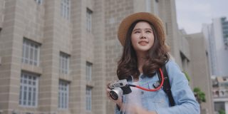 年轻的亚洲美女旅行者热情的用相机拍照是快乐的。在城市旅行的乐趣。周末活动快乐生活理念