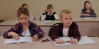 一群孩子坐在课桌前，一起举手。