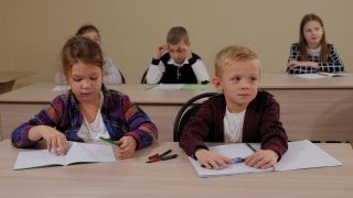 一群孩子坐在课桌前，一起举手。视频素材模板下载