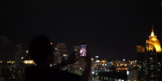 人们在一座建筑上拍摄城市的夜景。