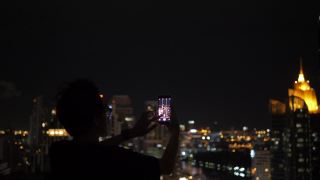 人们在一座建筑上拍摄城市的夜景。视频素材模板下载