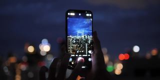 人们在一座建筑上拍摄城市的夜景。