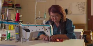 亚洲华人资深女企业家在工作室工作场所的缝纫机前缝制蜡染防护口罩