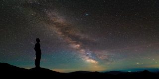 孤独的人站在繁星满天的山顶。间隔拍摄