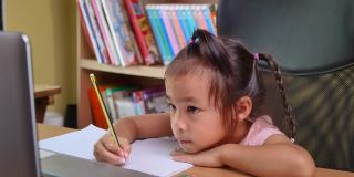 可爱的小女孩在家在线学习数学作业，在冠状病毒爆发期间保持社交距离。网络教育或家庭教育的概念。