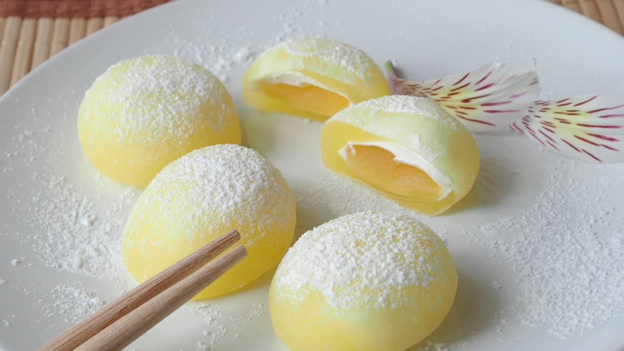 白盘子里的麻糬。黄色的米饭甜点，麻糬大多是日本的传统甜食