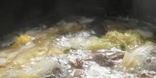 用电锅将煮熟的切片牛肉涮锅或寿喜烧和鸡蛋配蔬菜汤