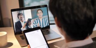 亚洲商人使用笔记本电脑和平板电脑在家庭办公室进行在线视频通话。