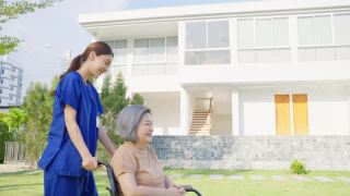 亚裔护理人员在户外照顾坐轮椅的残疾老妇人。美丽的女孩医生帮助和照顾在公园养老院做物理治疗的老年残疾患者。视频素材模板下载