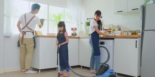 亚洲漂亮的父母教年轻的女孩打扫家里的厨房。可爱的爸爸妈妈帮助和支持小女儿在家打扫房间的地板。活动关系的概念。