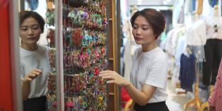 4K亚洲妇女在街市选购时尚饰品。