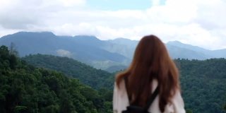 一个女旅行者看着美丽的山景的慢镜头