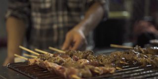 一位香港厨师在烤架上翻转烤肉串并涂上酱汁