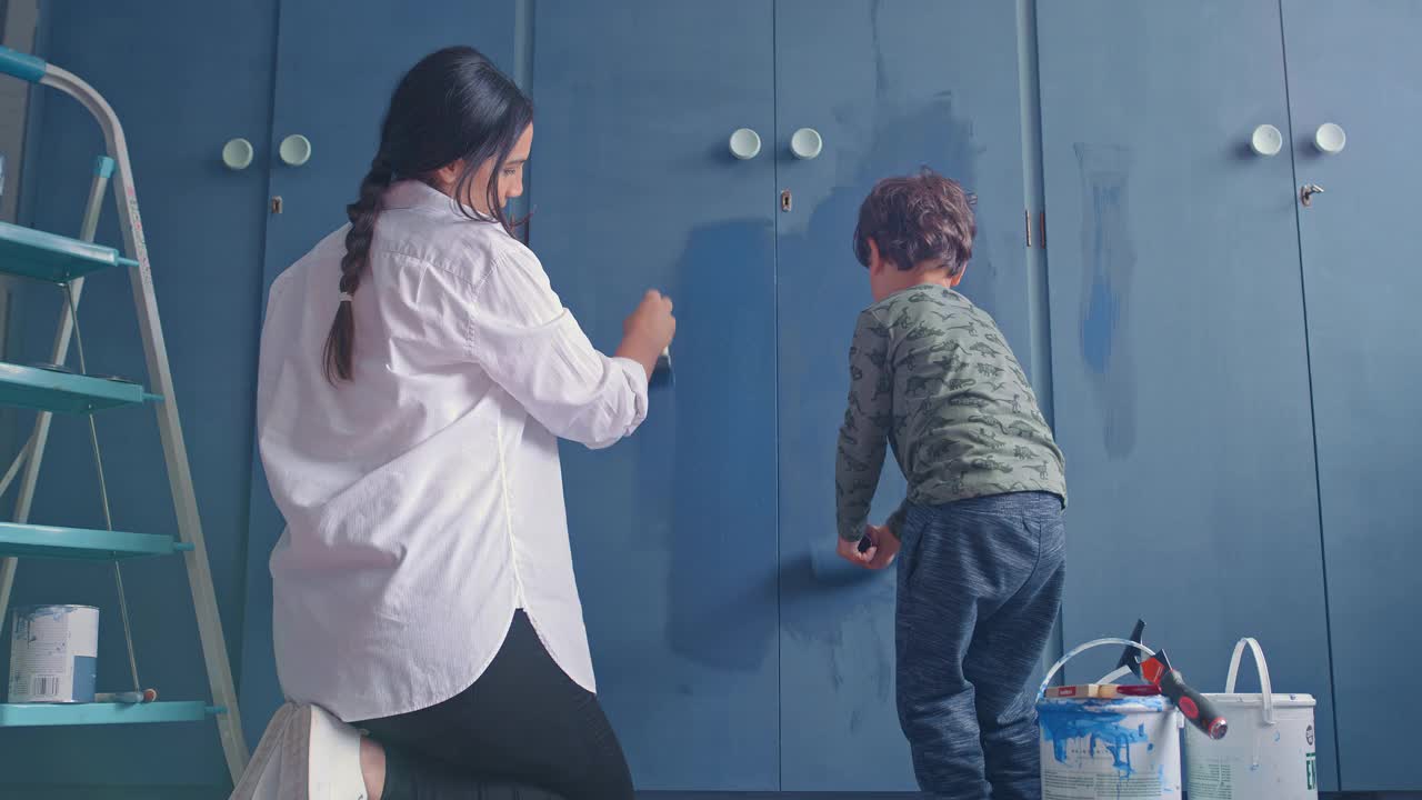 一个年轻女人和她可爱的儿子在家粉刷房间的4k视频