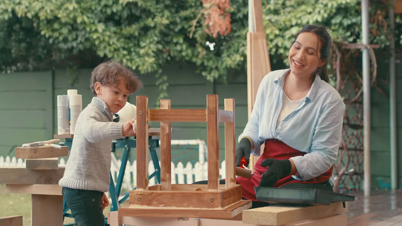 一个年轻女人和她可爱的儿子在家里做一个木制项目