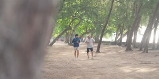 夏日清晨，4K亚洲老人和成年儿子一起在海滩上做运动。
